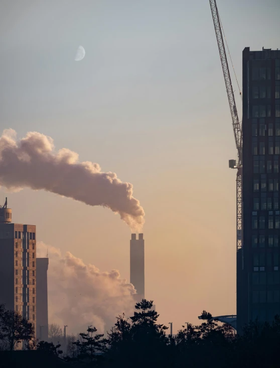 smoke billows from a smoke stack as the sun rises