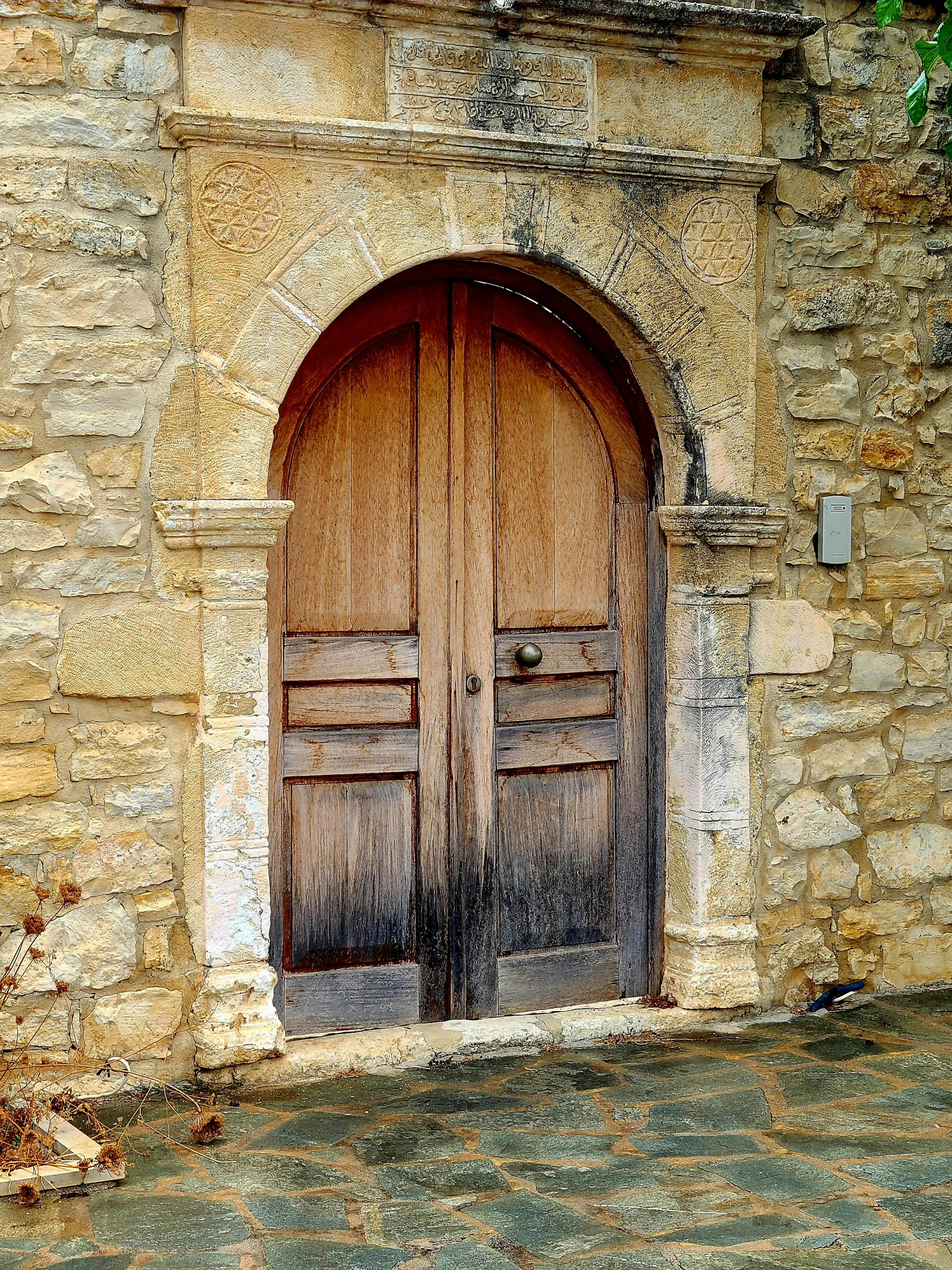 two wooden doors next to a stone wall