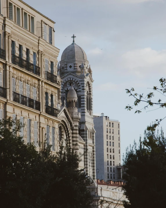 a church tower surrounded by trees in front of tall buildings