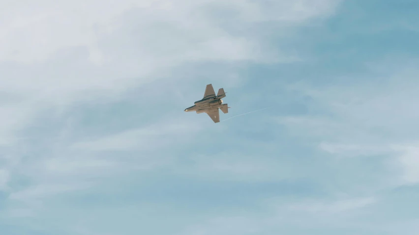 a fighter jet flying through a blue cloudy sky