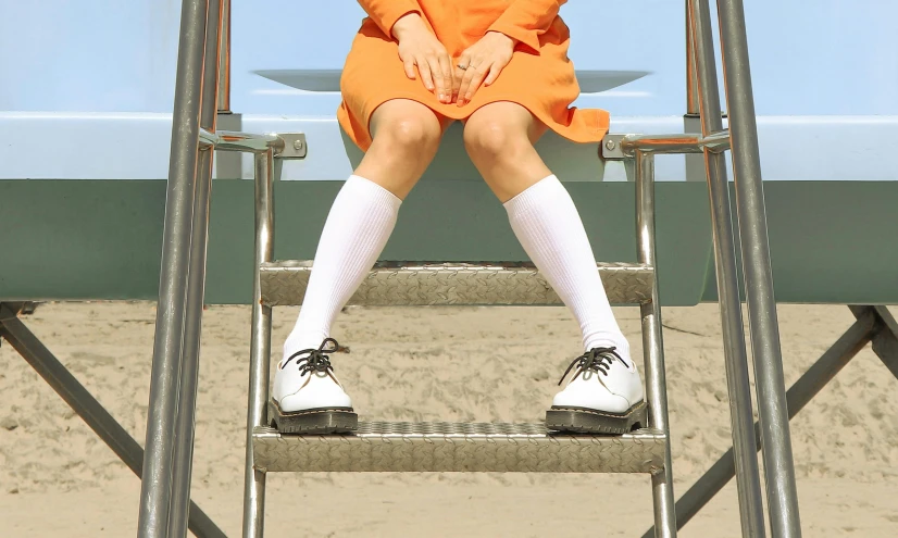 a girl sitting on a swing in the sand