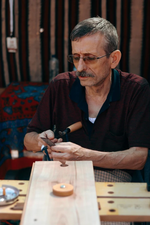 a man with a mustache grinds a piece of wood