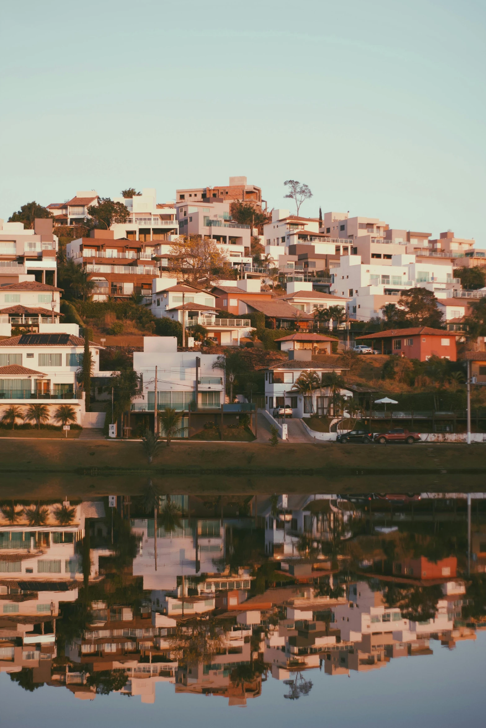 several houses on a hill are on a hilltop, reflecting in the water