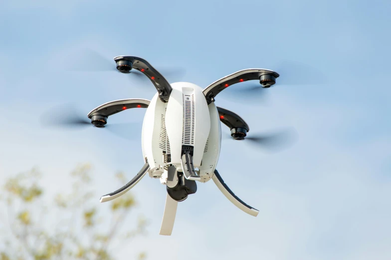 the back side of a black and white remote controlled quad rotor flying overhead