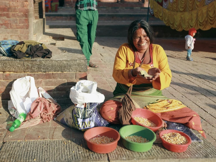 a woman sitting on the ground next to bowls and rice