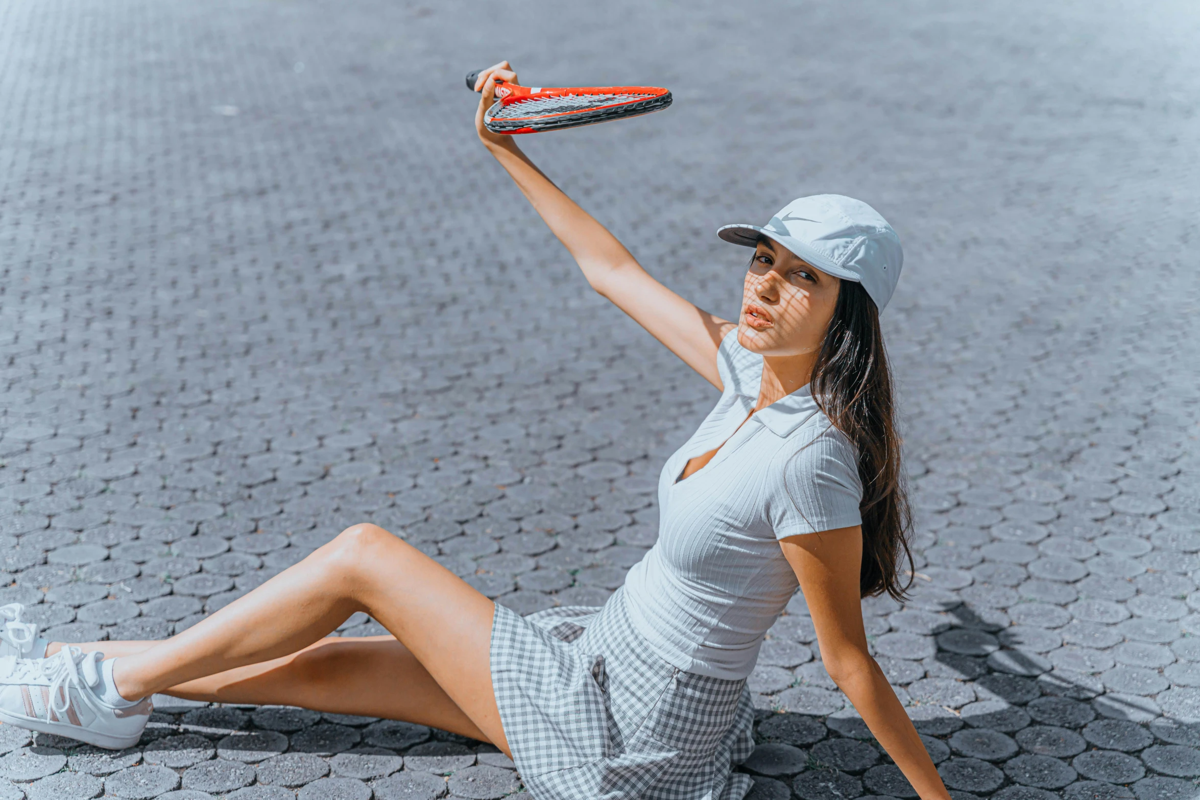 a woman in a white dress and hat poses holding a tennis racquet