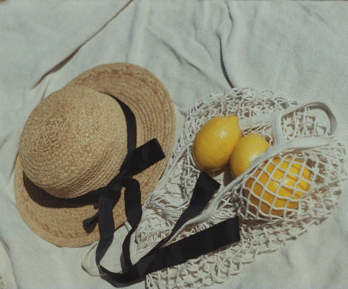 a hat, bag and fruit on a towel