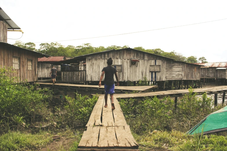 a man is walking on a wooden plank over the water