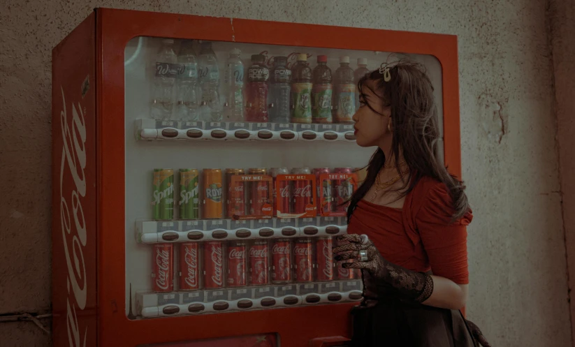 a woman holding onto a drink bottle near a vending machine