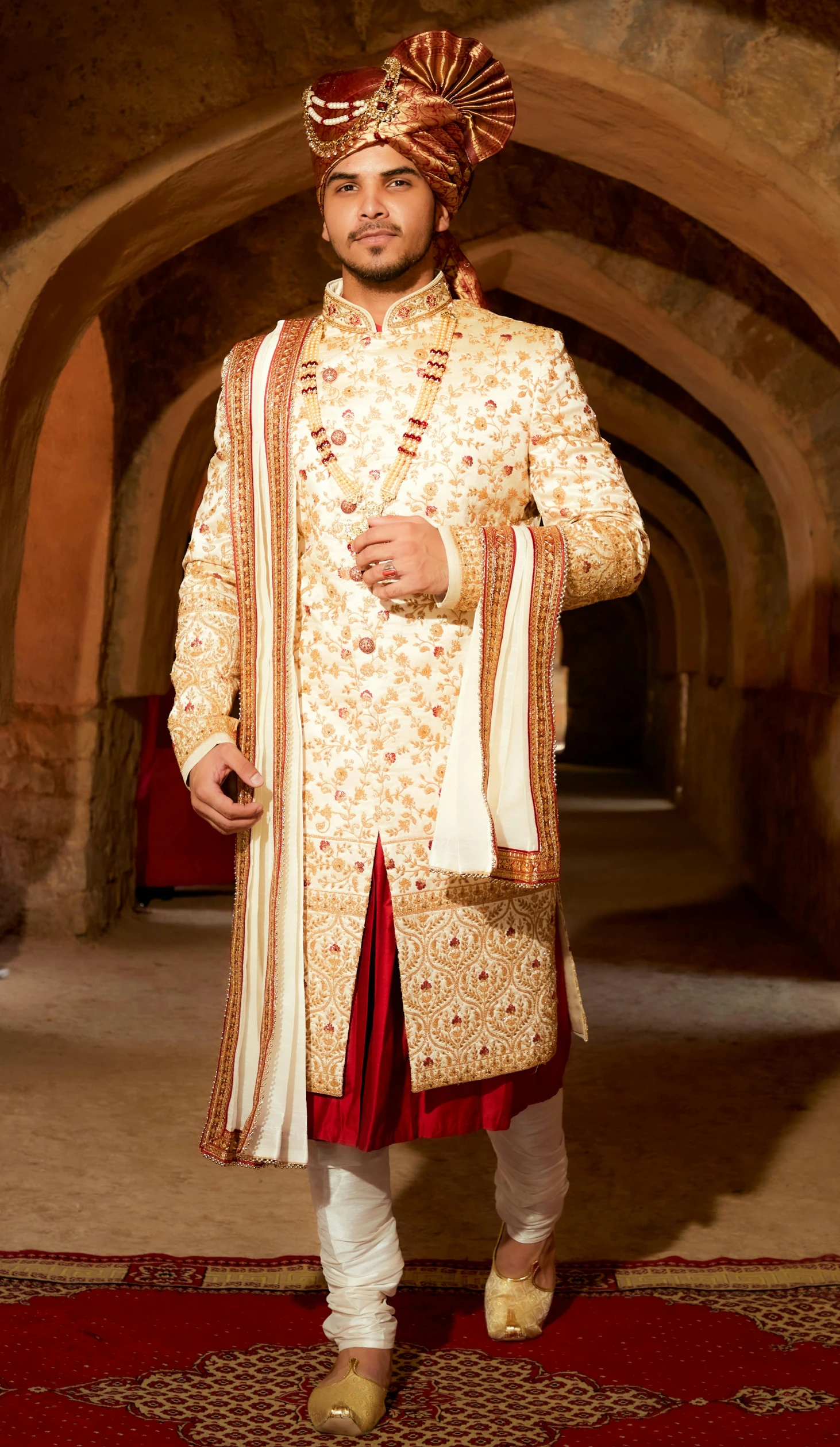 a man in a traditional indian outfit stands smiling for the camera