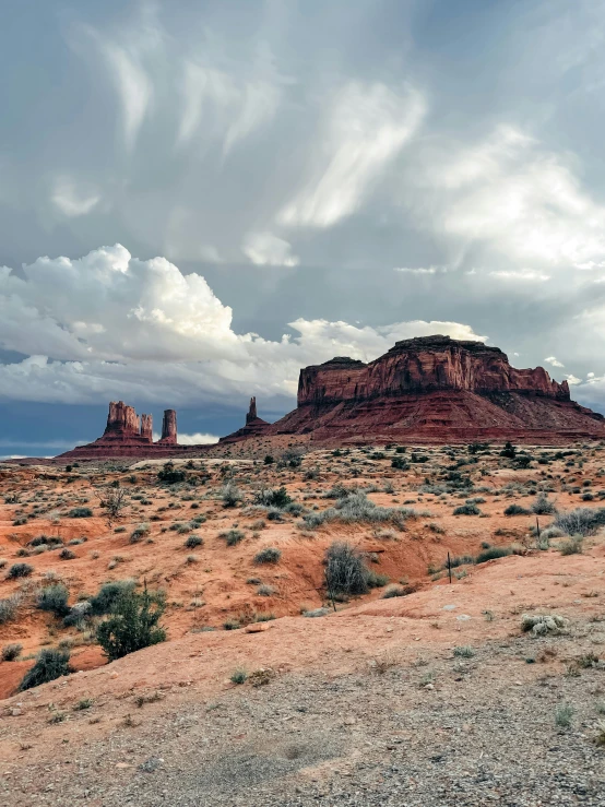 clouds cover the mountains in the distance with sand and trees