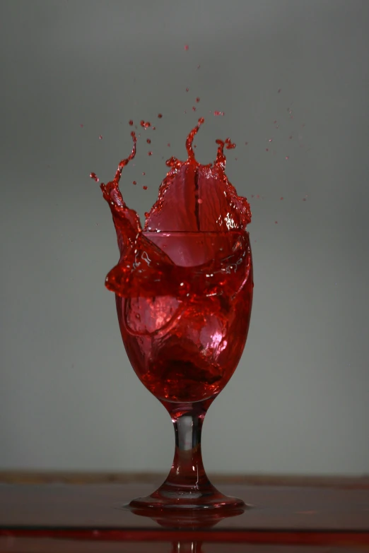 a large red glass sitting on top of a wooden table
