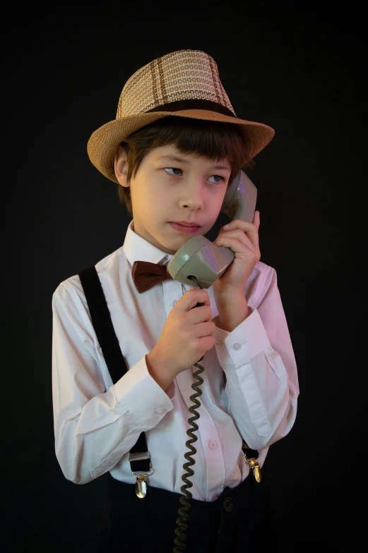 a  in a bow tie and fedora talking on an old telephone