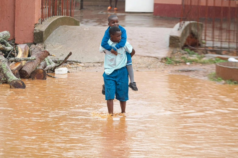 a woman holds her child while standing in flooded street