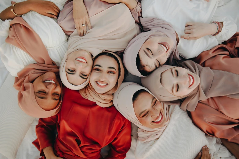 five women in headscarves lying on a bed