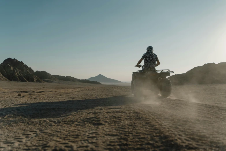 a man riding an atv down a dirt road