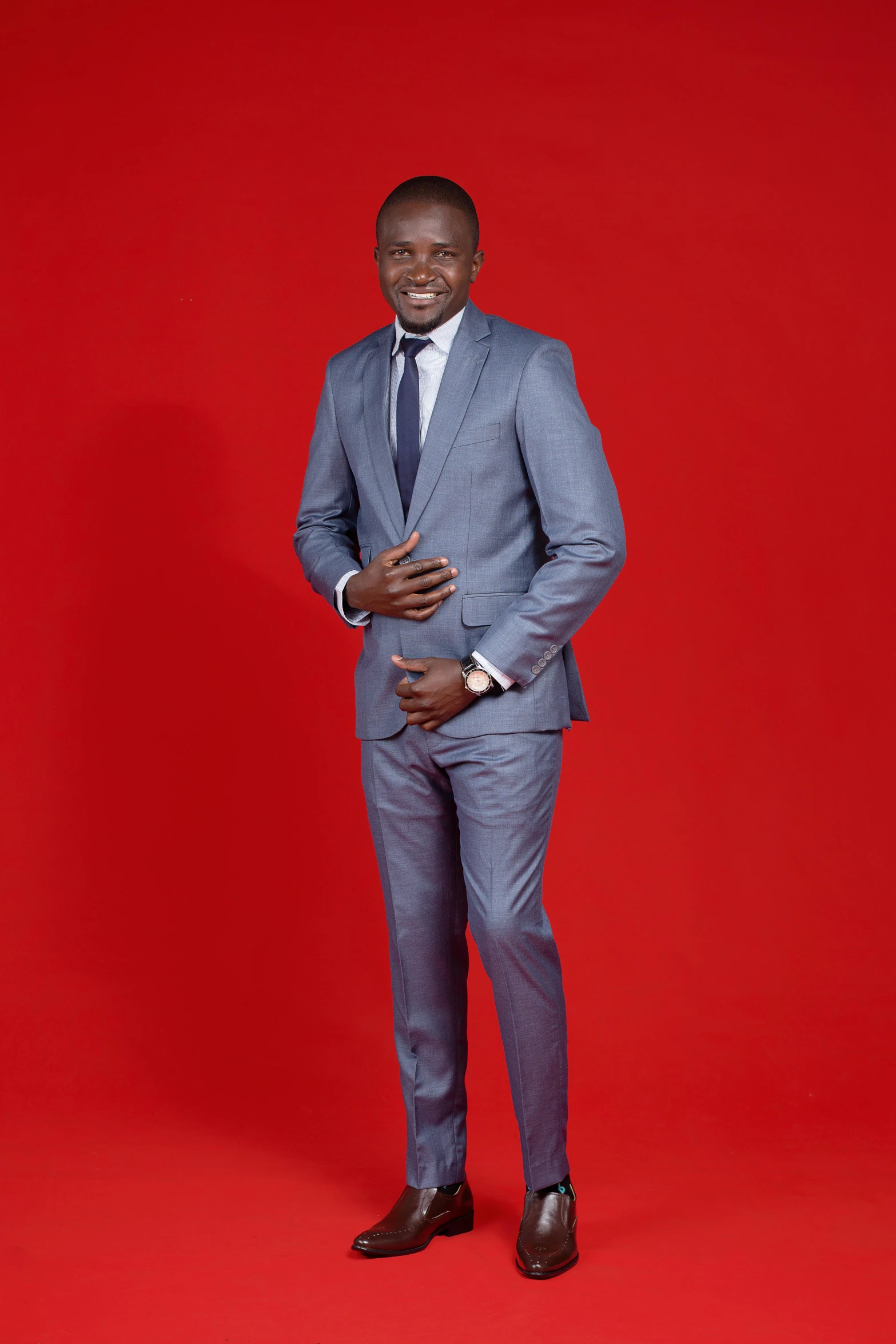 a young black man wearing a suit standing in front of a red backdrop