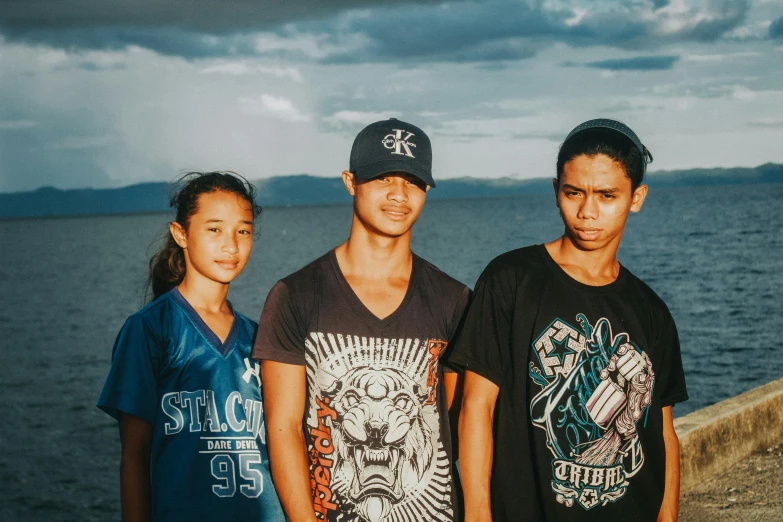 three young people standing next to the water