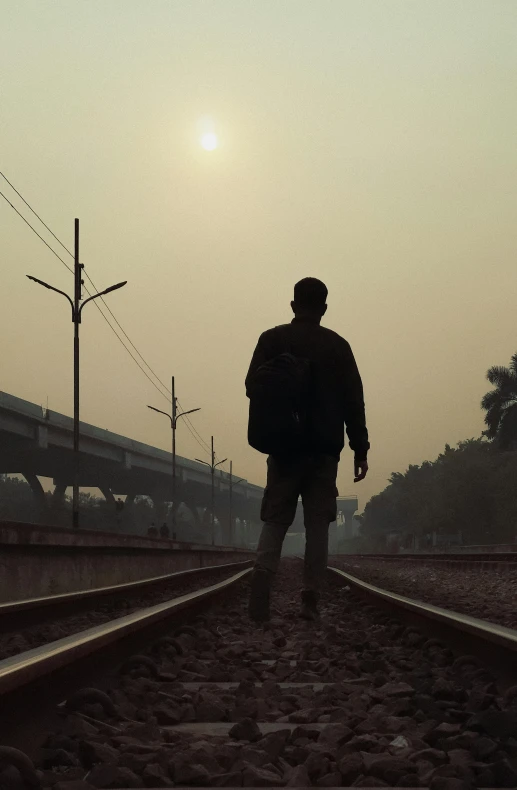 a silhouette image of a man walking down train tracks