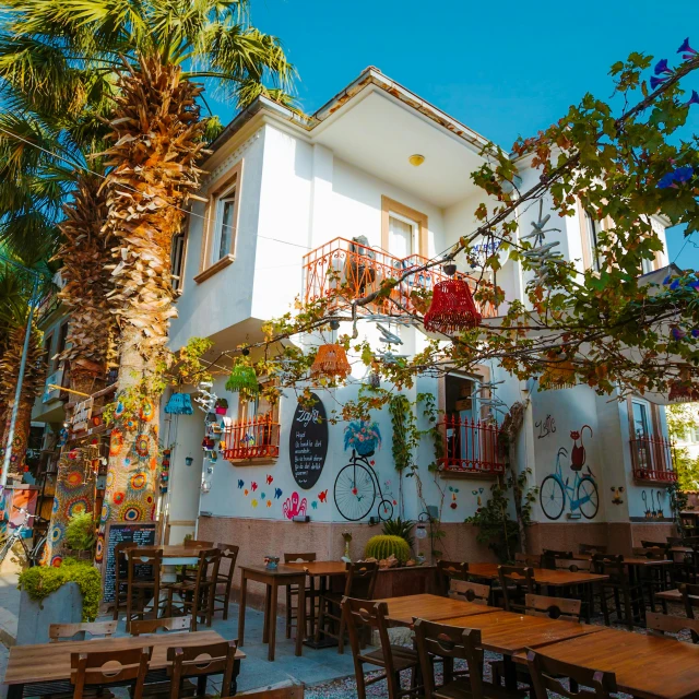 several tables and chairs around outside with trees and flowers