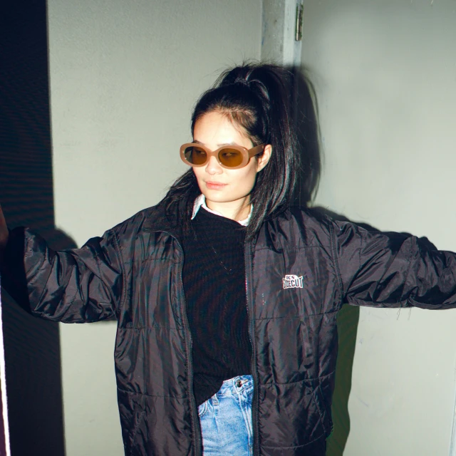 a woman in an oversized black jacket and sunglasses