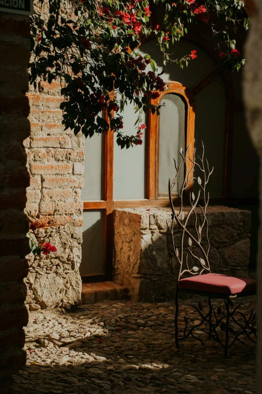 an antique chair sitting on the pavement in front of an archway and window