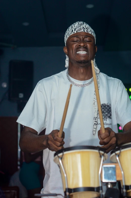 a man holding a drum and drumstick next to another person