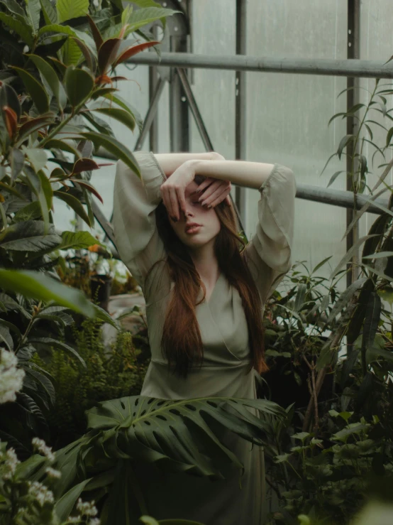 a woman with long red hair holds her hand on top of her head