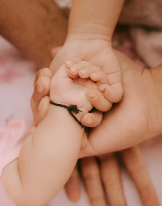 a baby held by an adult's hand