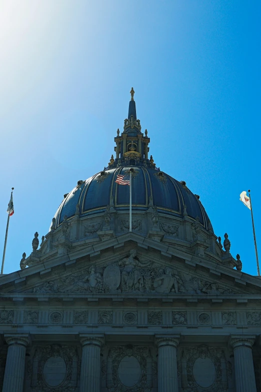 the flagpole atop a building with statues on it