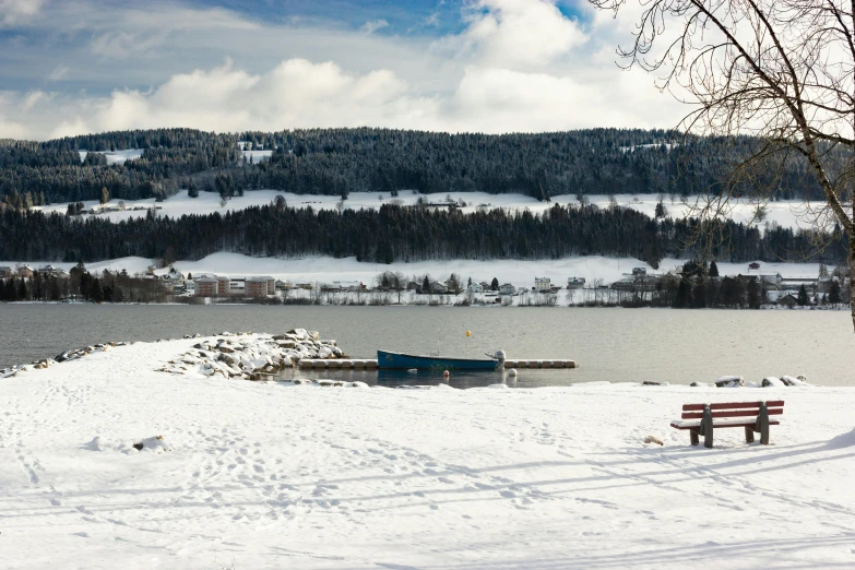 a bench is on the snow by the water