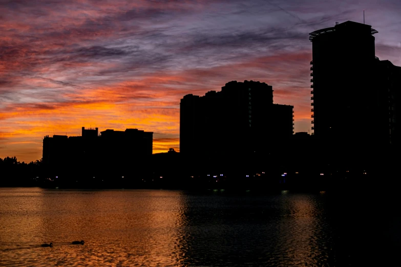 buildings are silhouetted against a sunset in the city