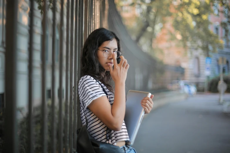 a woman in striped shirt talking on cellphone while holding a book