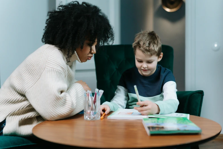 a woman and child are at a table with books