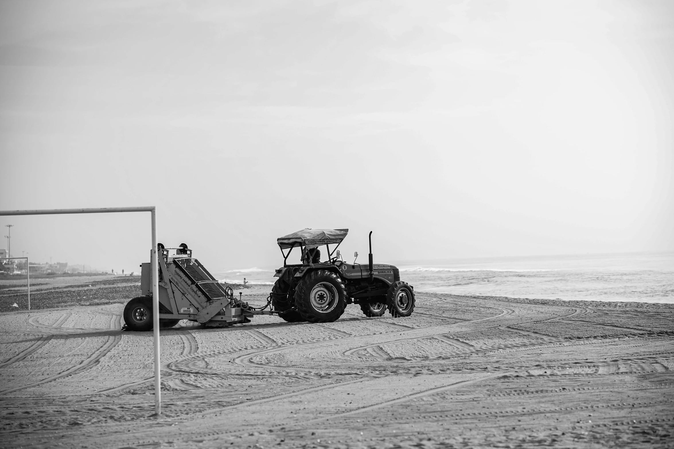 a tractor sitting parked on the beach with a boat