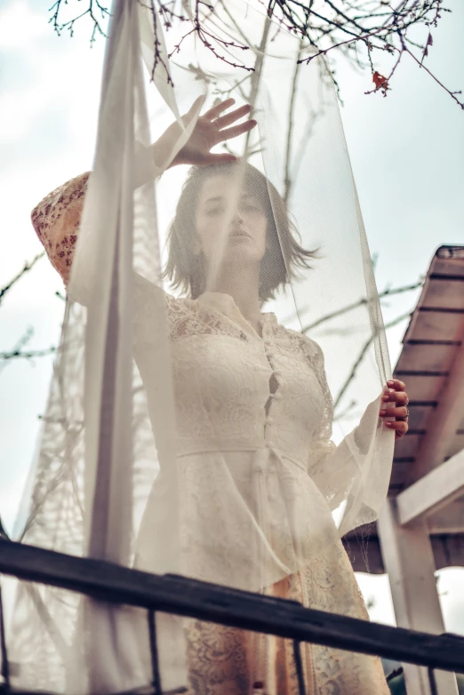 a woman in white dress standing near a fence