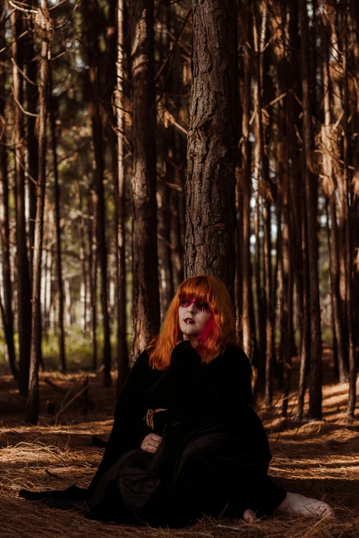 a girl with red hair sitting under a tree