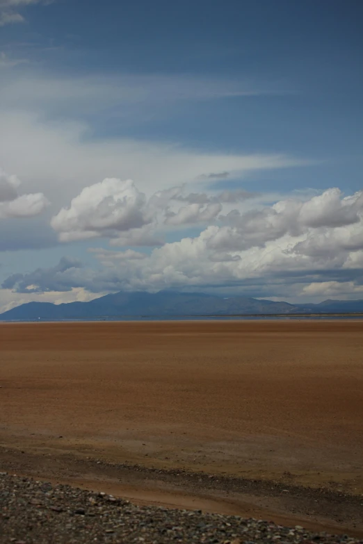 an empty plain has a few clouds and brown sand