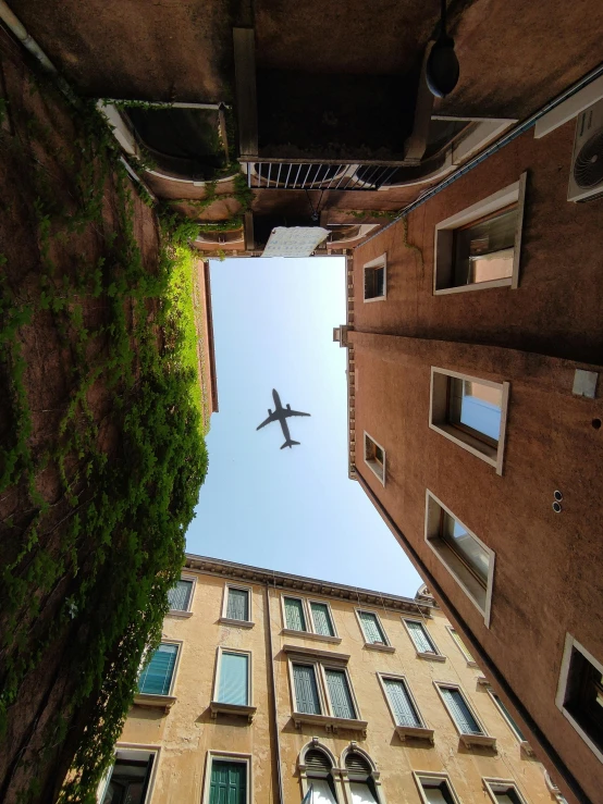 looking up at an airplane flying above building and windows