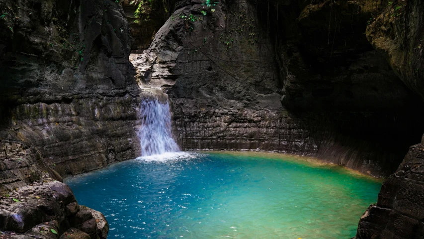 waterfall with blue water in rock pool, with waterfall, trees and rock