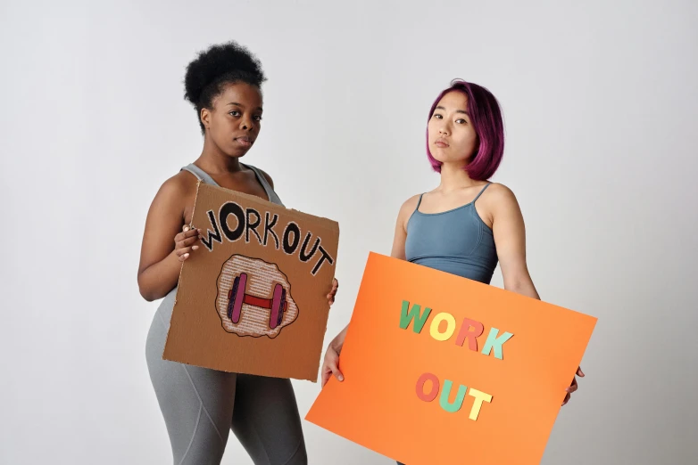 two women holding cardboard signs in front of their faces