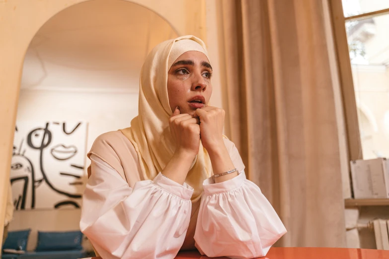 a person sitting at a table with her hand under her chin