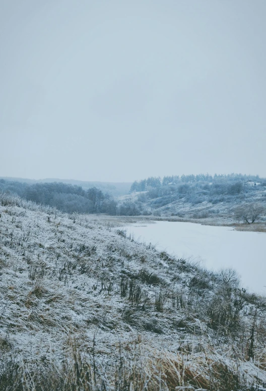 a field with snow covered grass and a river