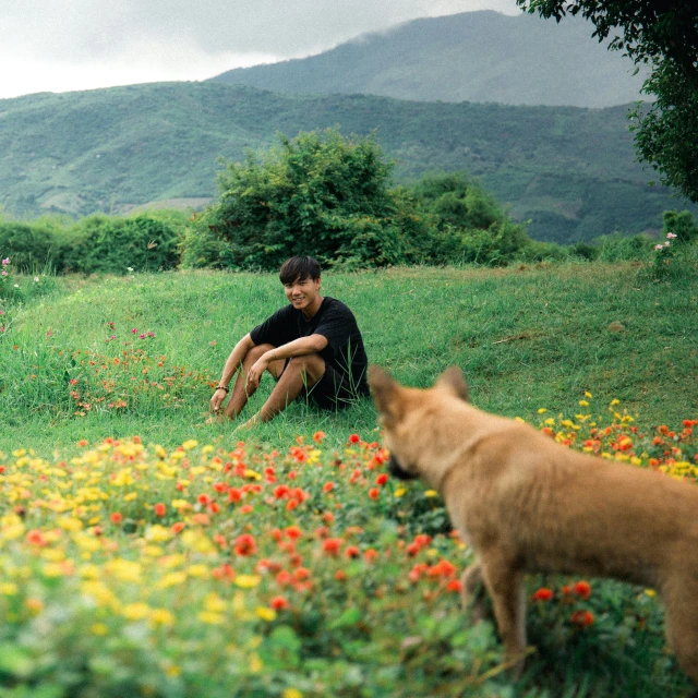 a person sits on a hill with a cat near by