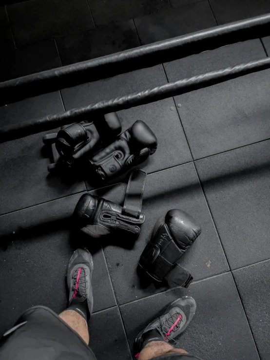 feet with pads, gloves and skateboard lying on black tiled floor