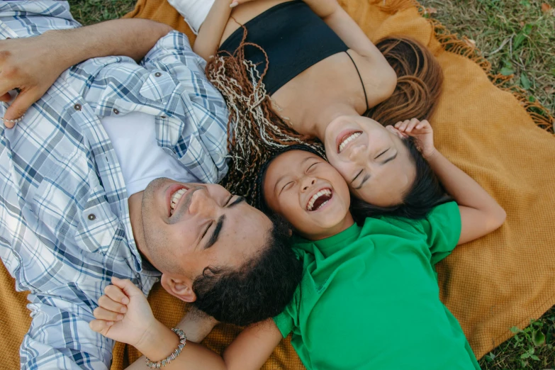 a man and three young children are laying on a blanket on the ground