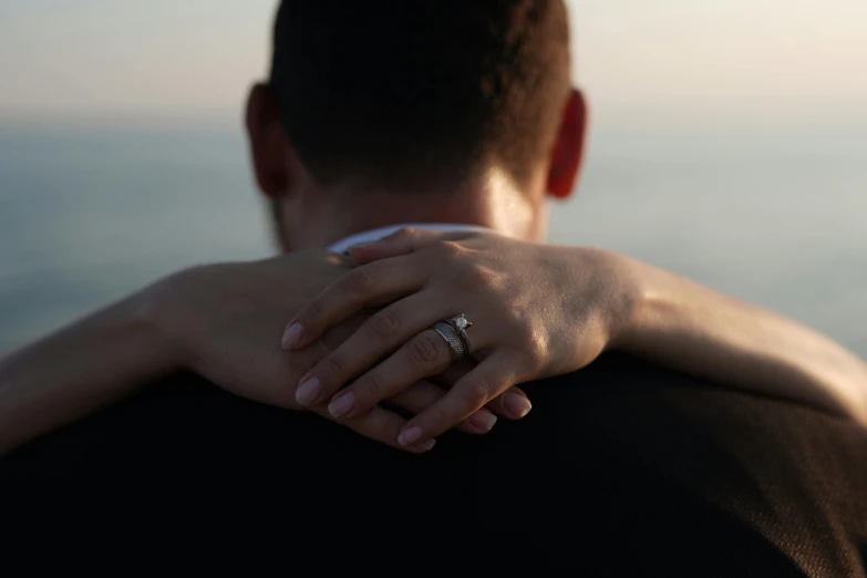 man and woman holding each other while looking at the ocean