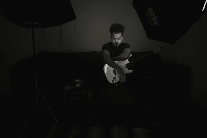 a man holding an acoustic guitar in the dark