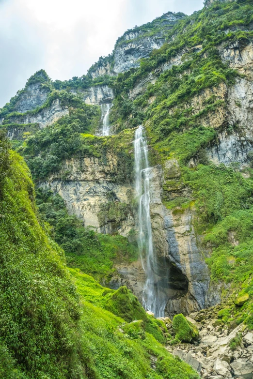 the mountains surrounding the waterfall are green