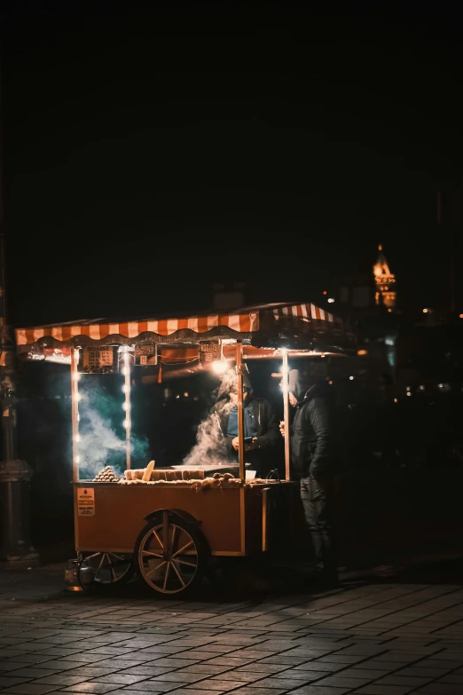 a person stands at a food cart, with lights